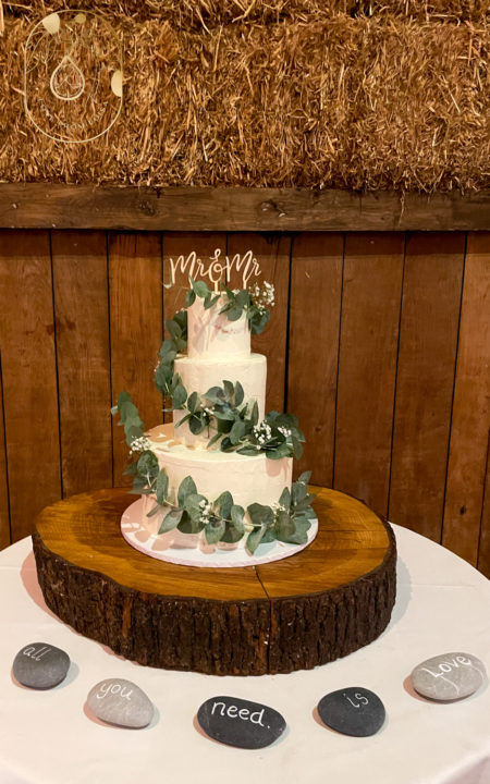 Mr and Mr Wedding Cake delivered to Pangdean Barn. Rustic wedding cake on log with Barn backdrop