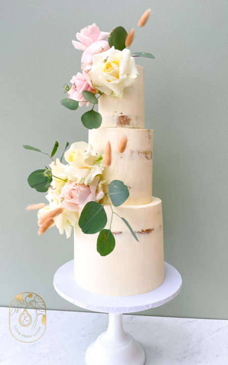 Tree tier wedding cake in semi-naked design with roses and eucalyptus