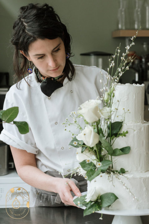 Three tier wedding cake with white roses and greenery