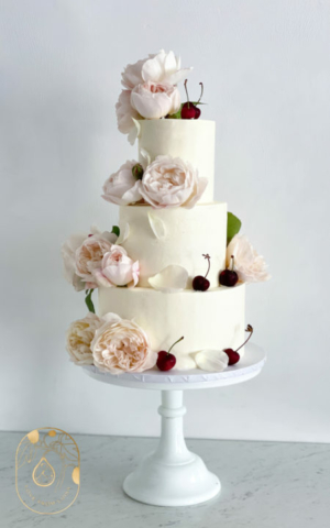 Three tier vegan buttercream wedding cake with flowers and cherries