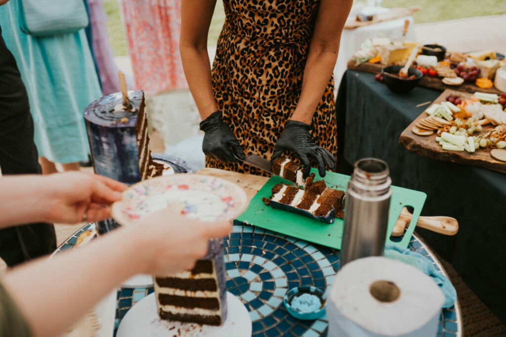 Image of Luisa cutting a three tier wedding cake into coffee size portions