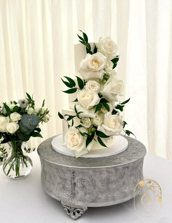 Three tier wedding cake with white roses and greenery