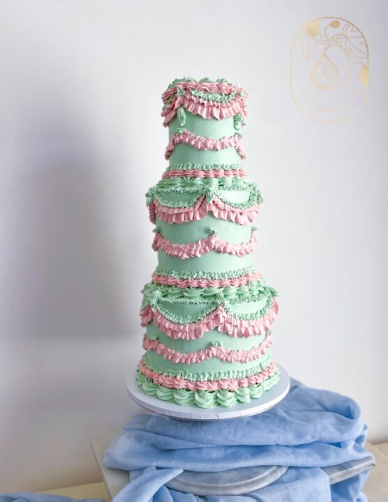 Three tier pastel pink and green vintage piped wedding cake with cherries 