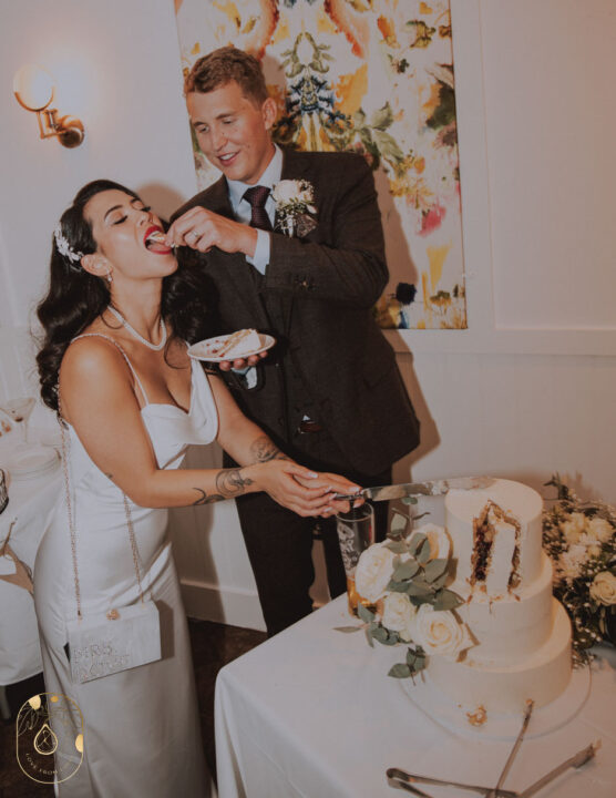 Wedding cake flavours - Image shows a couple cutting their wedding cake and the groom feeding the bride cake